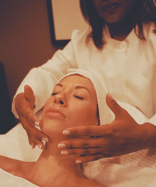An esthetician’s hands on a client’s face during a facial