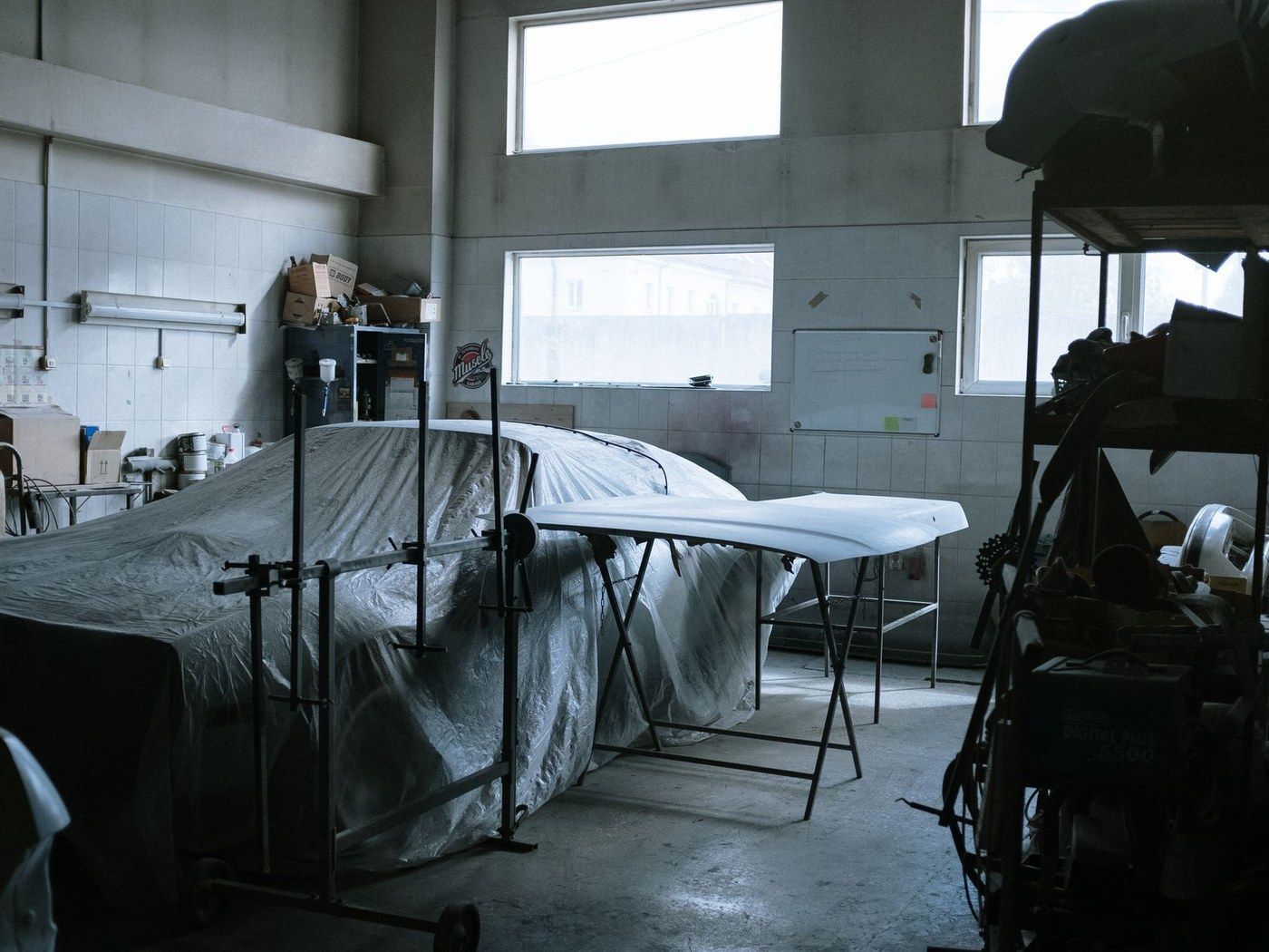 A car under a cover on a workshop floor