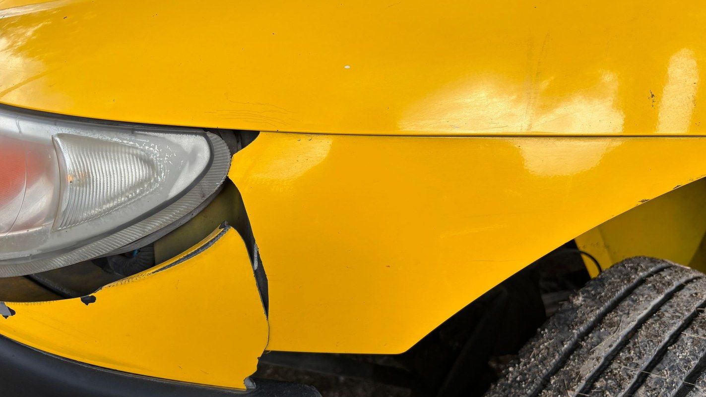A yellow car with a crushed front bumper