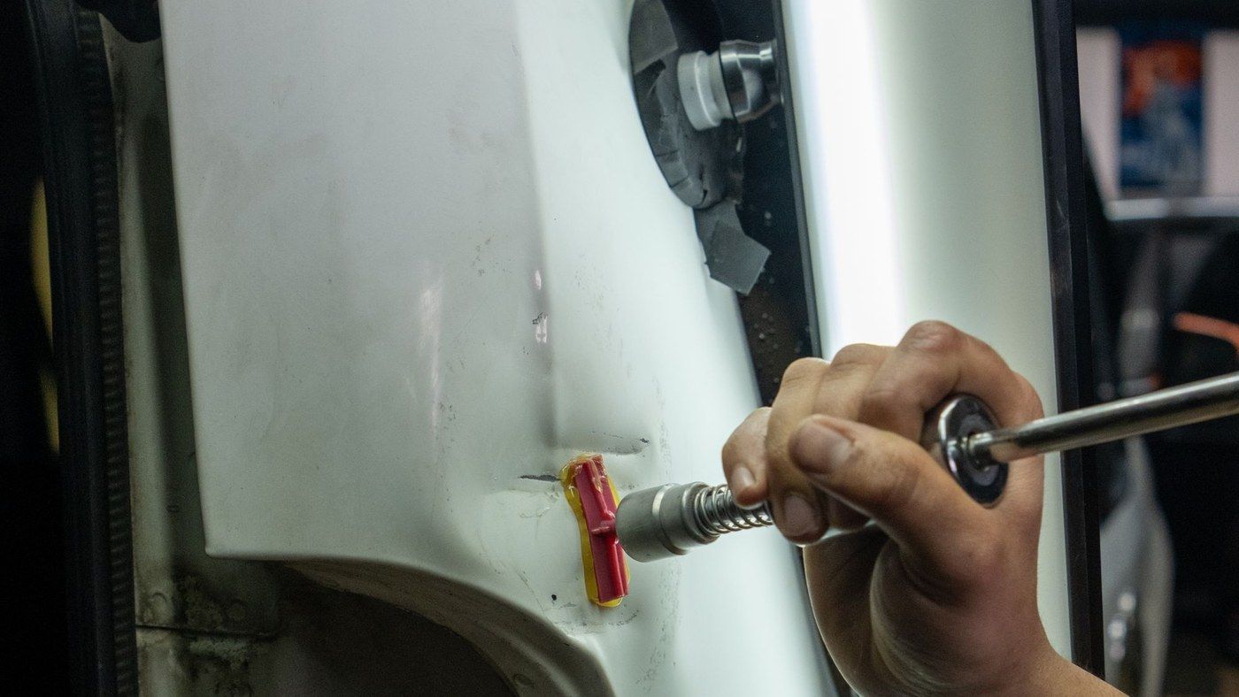 Dent repair tools against a white door panel under a reading light