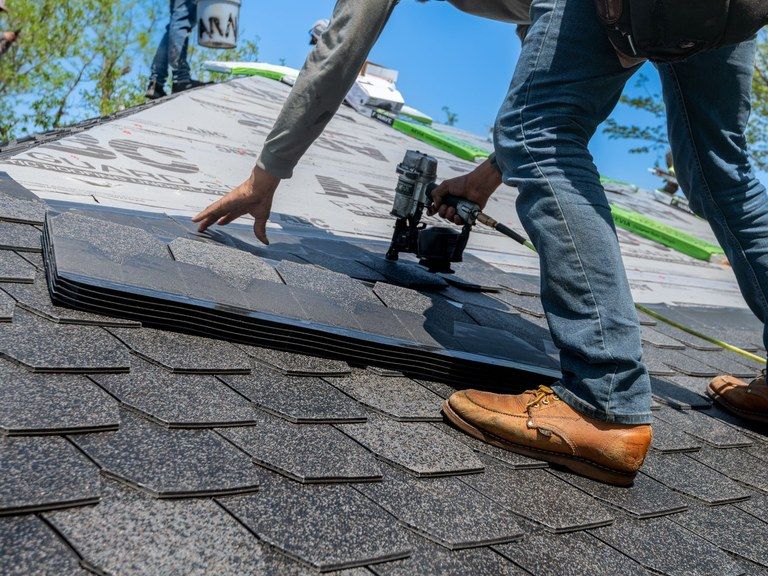 A roofer nailing new shingles
